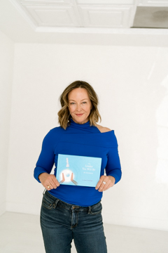 Anese Cavanaugh in a blue top holding up her book The Leader You Will Be